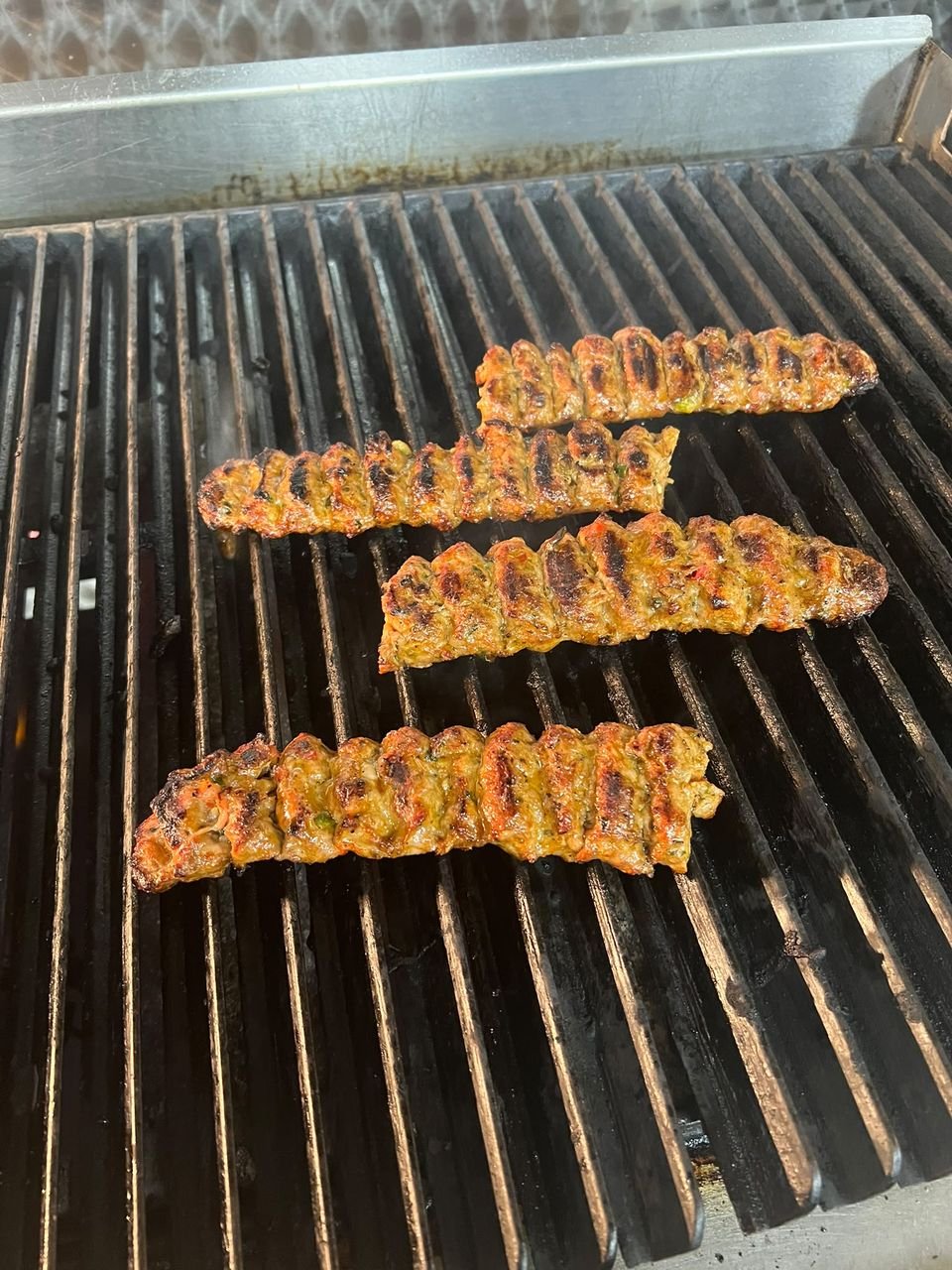 Adana kebabs cooking on the grill